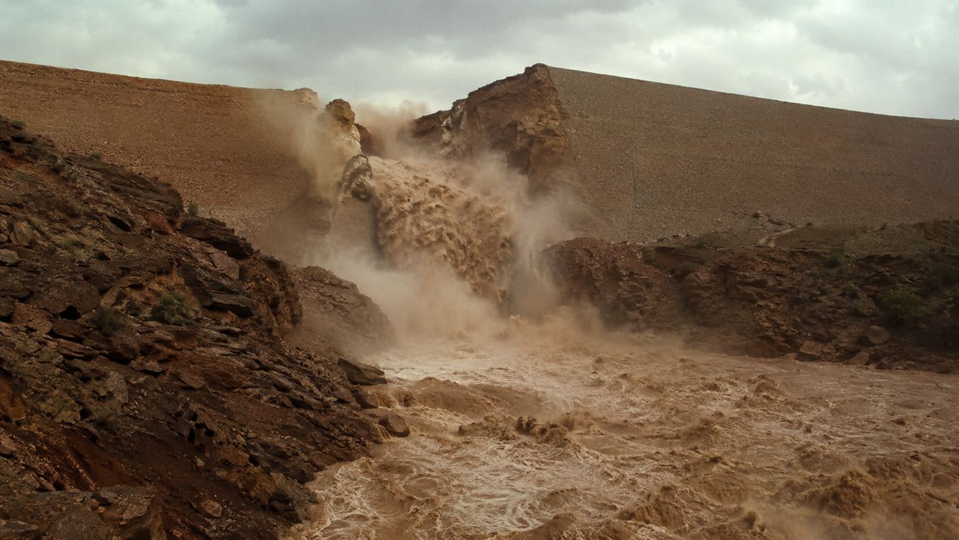 The Teton Dam breaching in 1976, a torrent of brown water bursting through a huge gap in the earthen dam into the canyon below