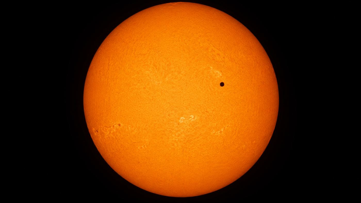 The small black disc of Venus crossing the bright face of the Sun during a transit