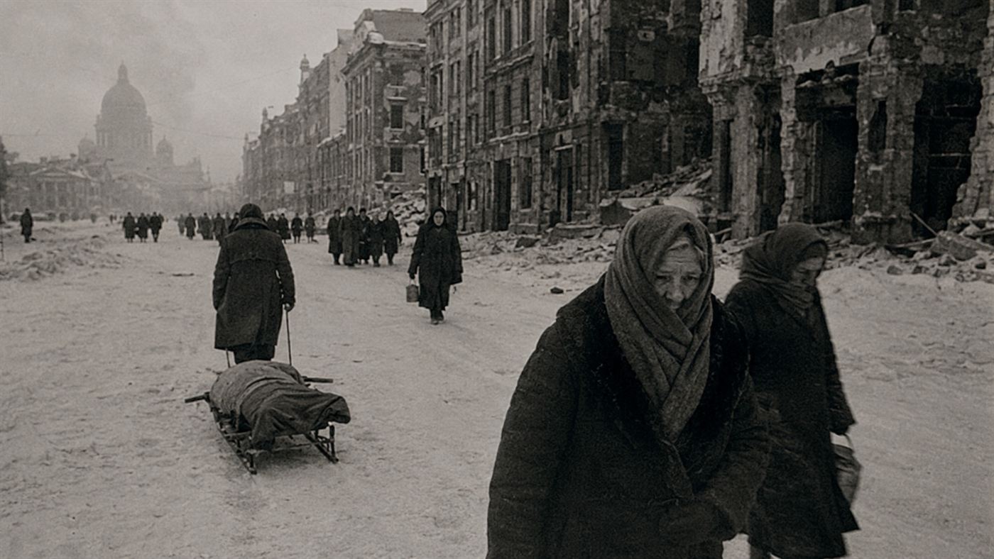 A bleak frozen street in besieged 1940s Leningrad with gaunt figures in deep winter