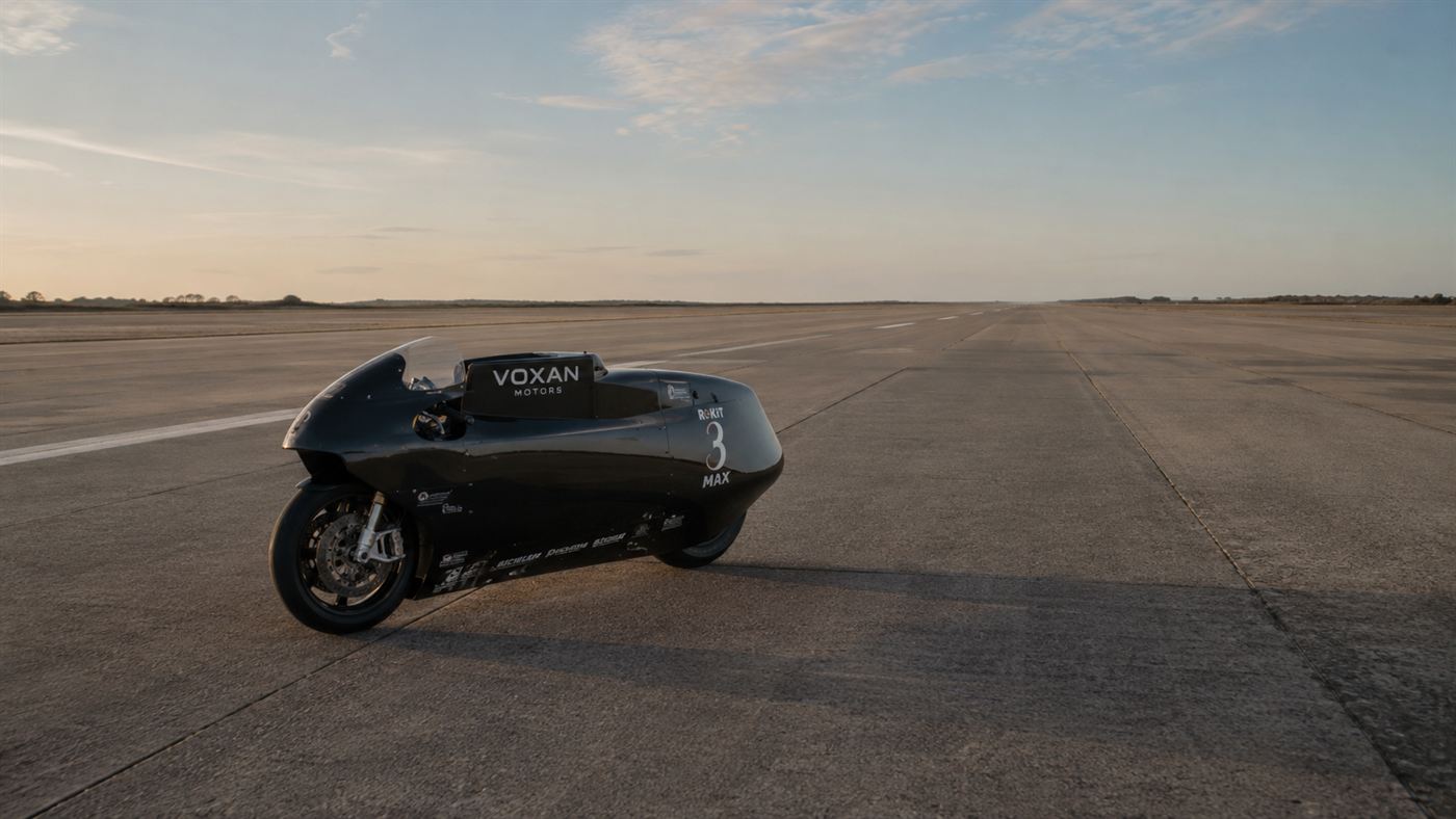 A futuristic electric record motorcycle alone on a vast empty runway stretching to the horizon