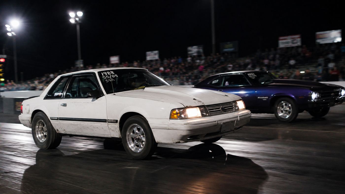The White Zombie launching off the line just ahead of a muscle car at a floodlit drag strip