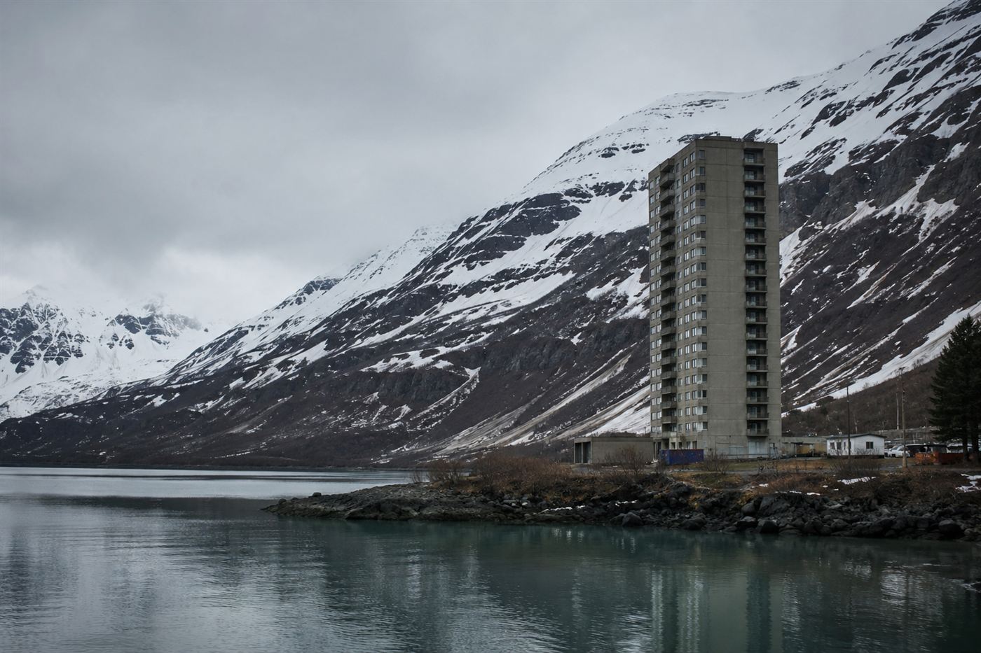 The Begich Towers, the 14-story building where almost all of Whittier, Alaska lives, standing alone beneath snowy mountains by a fjord