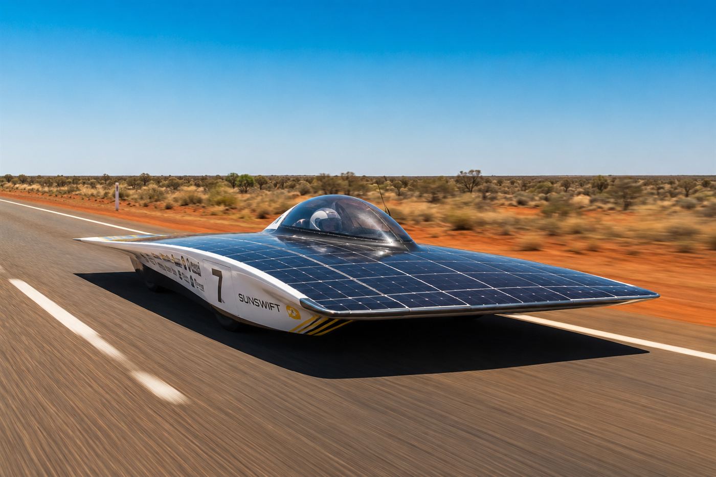 A sleek low flat solar-panelled race car driving along an empty outback highway under bright sun in the World Solar Challenge