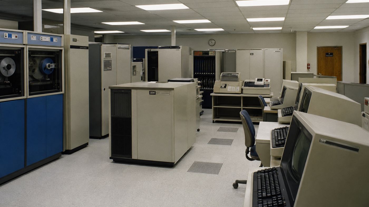 A 1980s university computer room with mainframe cabinets and CRT terminals