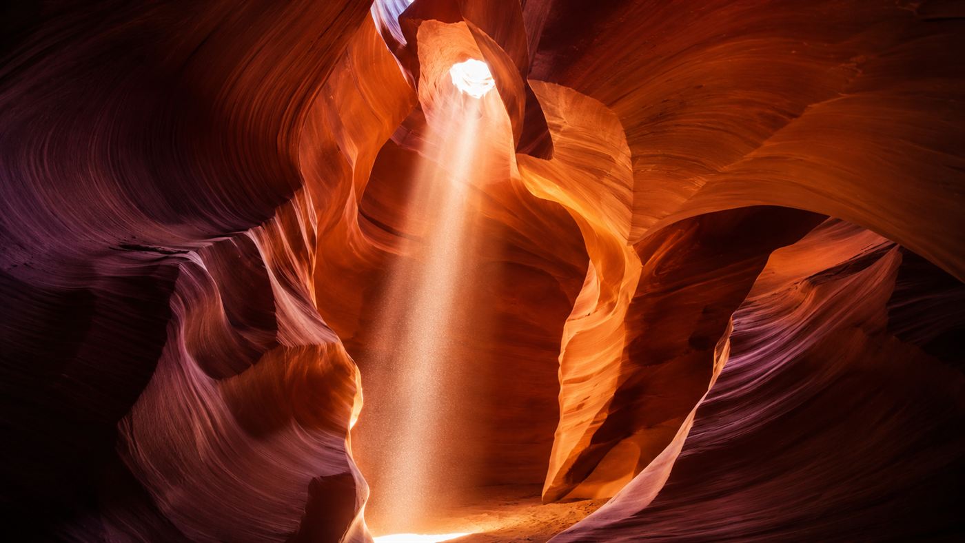 A shaft of sunlight falling through the glowing orange sandstone walls of Antelope Canyon, a narrow slot canyon in Arizona