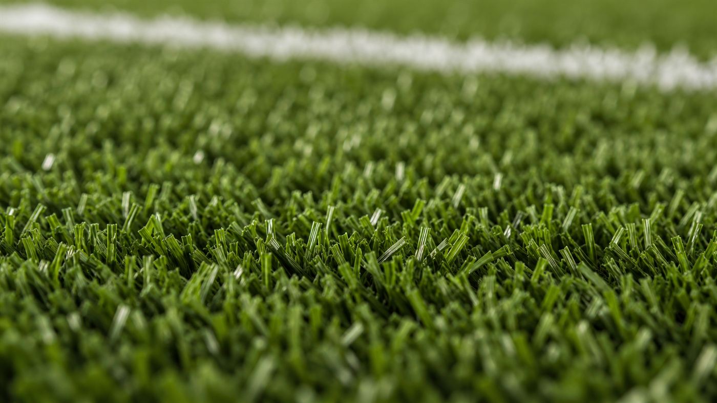 A close-up of bright green artificial turf made of nylon blades on a stadium field