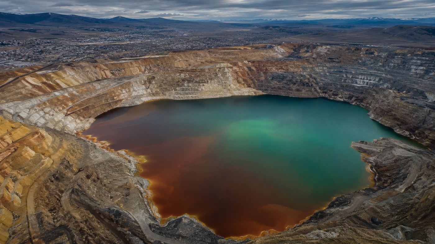 The Berkeley Pit, a mile-wide flooded copper mine in Butte, Montana, its acidic rust-colored water ringed by terraced rock walls