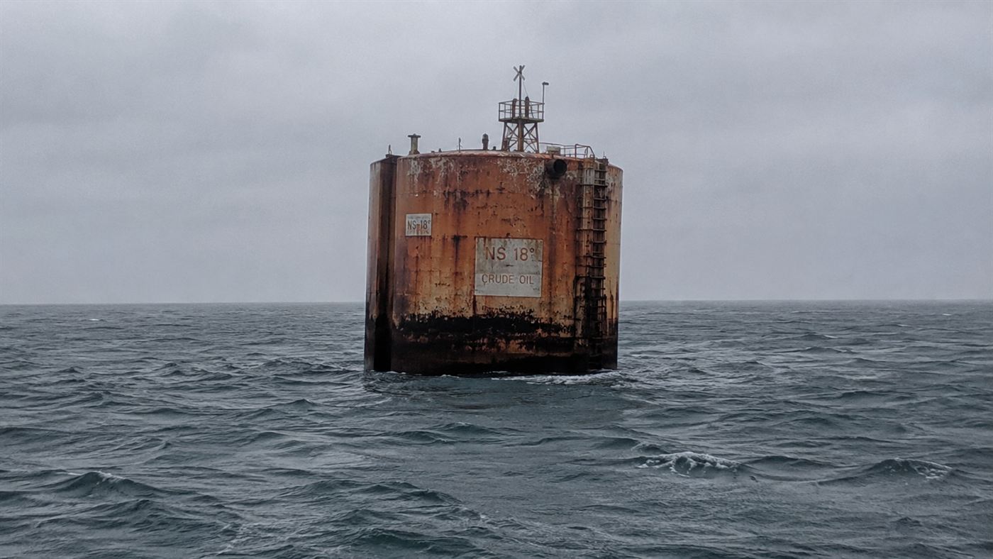 The tall cylindrical Brent Spar oil storage buoy floating alone in the grey North Sea