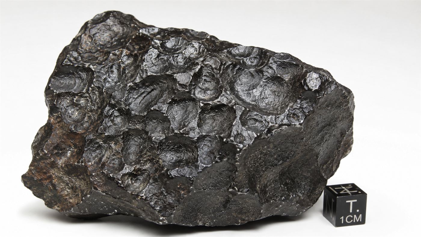 A dark iron meteorite fragment from Canyon Diablo resting on a clean laboratory bench