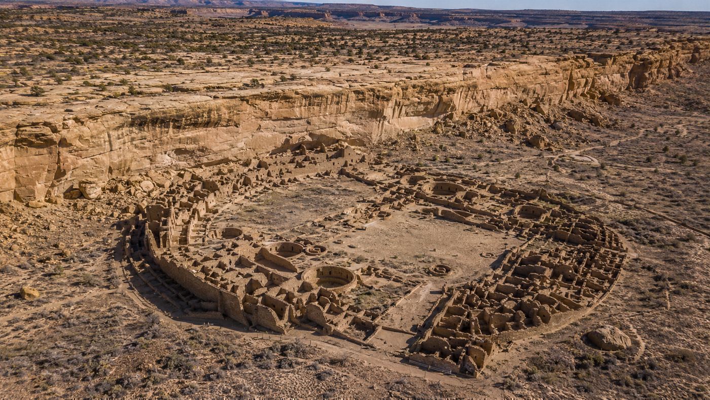 Aerial view of the great semicircular stone ruins of Pueblo Bonito in Chaco Canyon, New Mexico, set in a bare desert canyon