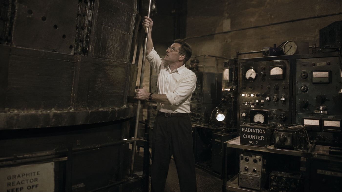A scientist pulling a control rod beside vintage instruments at Chicago Pile-1 during the first nuclear chain reaction