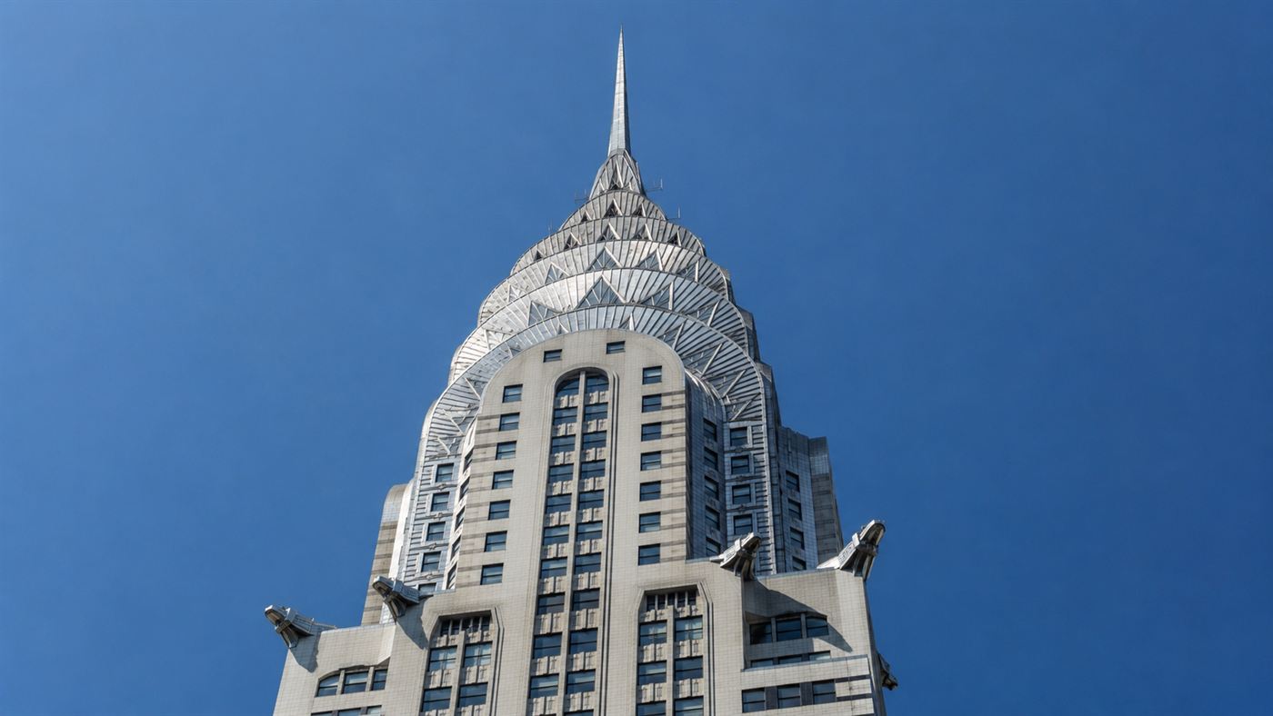 The gleaming stainless-steel Art Deco crown and spire of the Chrysler Building shining against a blue sky