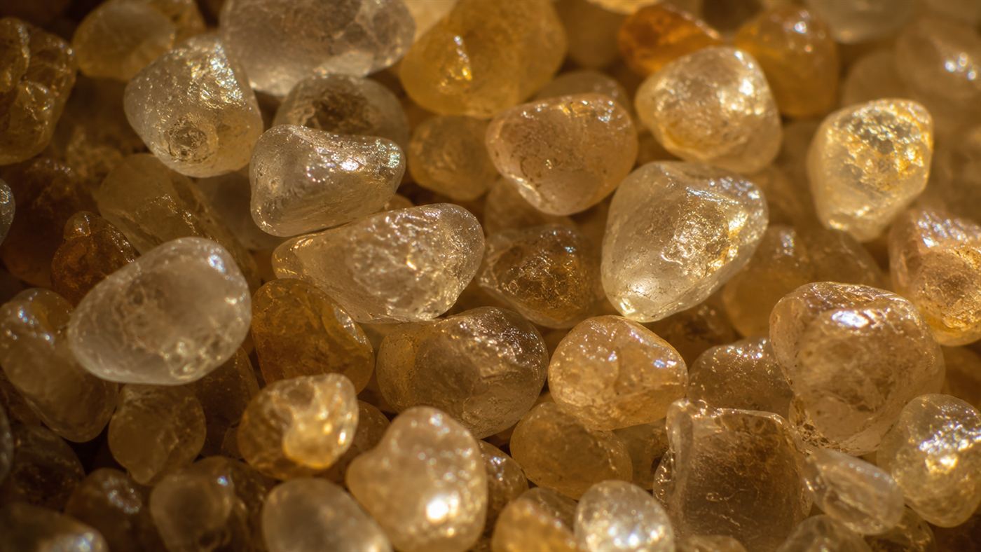An extreme close-up of rounded, evenly sized golden desert sand grains, the kind that can produce booming sand