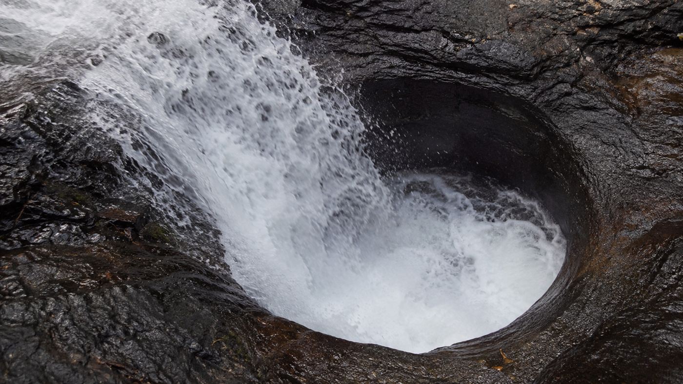 The churning dark pothole at Devils Kettle where half the Brule River disappears into the rock