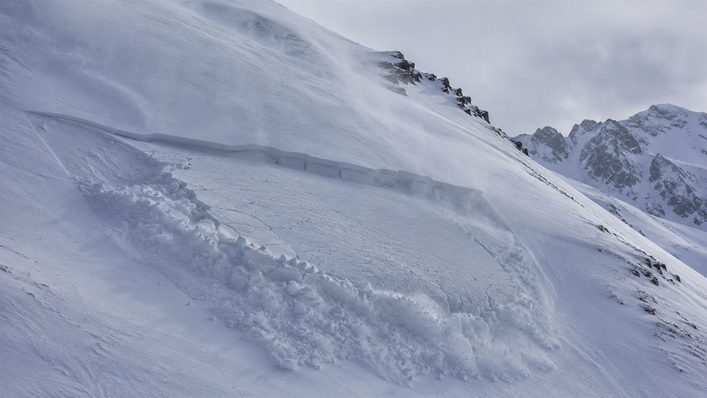 A small slab avalanche releasing on a snowy mountain slope, the proposed cause of the Dyatlov Pass incident