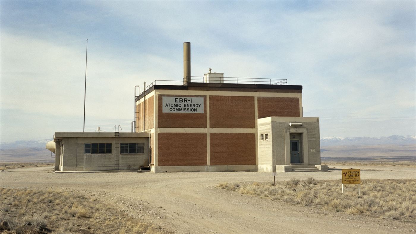 A low 1950s research reactor building standing alone in the flat empty Idaho desert