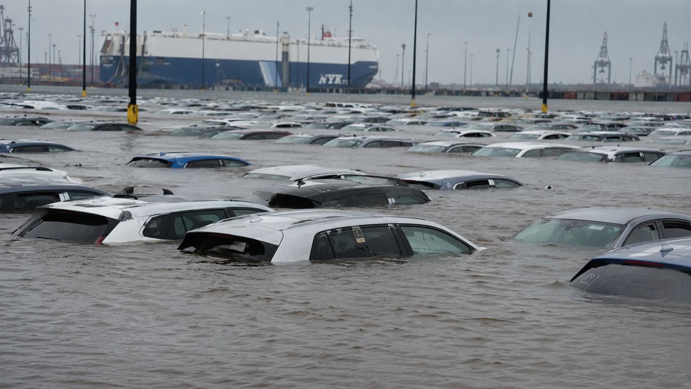 Rows of new cars half-submerged in floodwater at a port after a hurricane storm surge