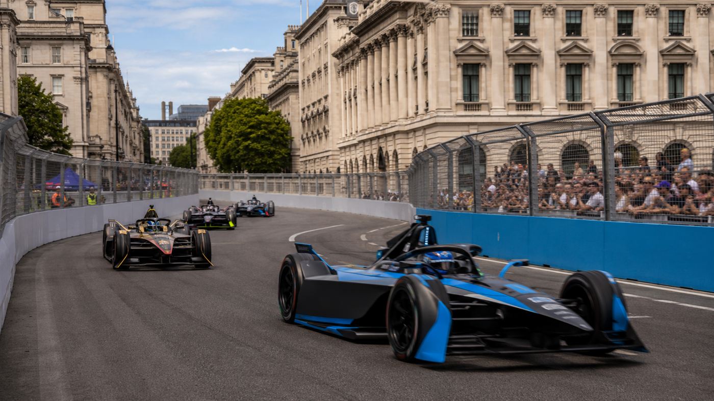 Formula E single-seaters racing on a temporary street circuit through a city center lined with crowds