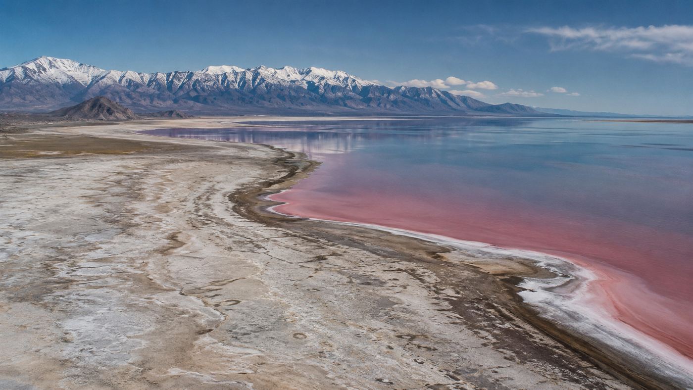 An aerial view of the shrinking Great Salt Lake in Utah, pale exposed lakebed and receding shoreline around bright saline water