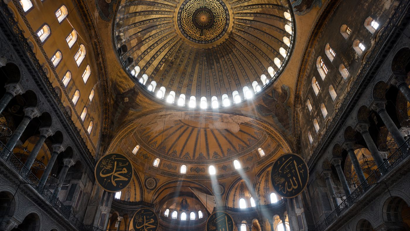The vast golden dome of Hagia Sophia ringed with arched windows, seen from inside