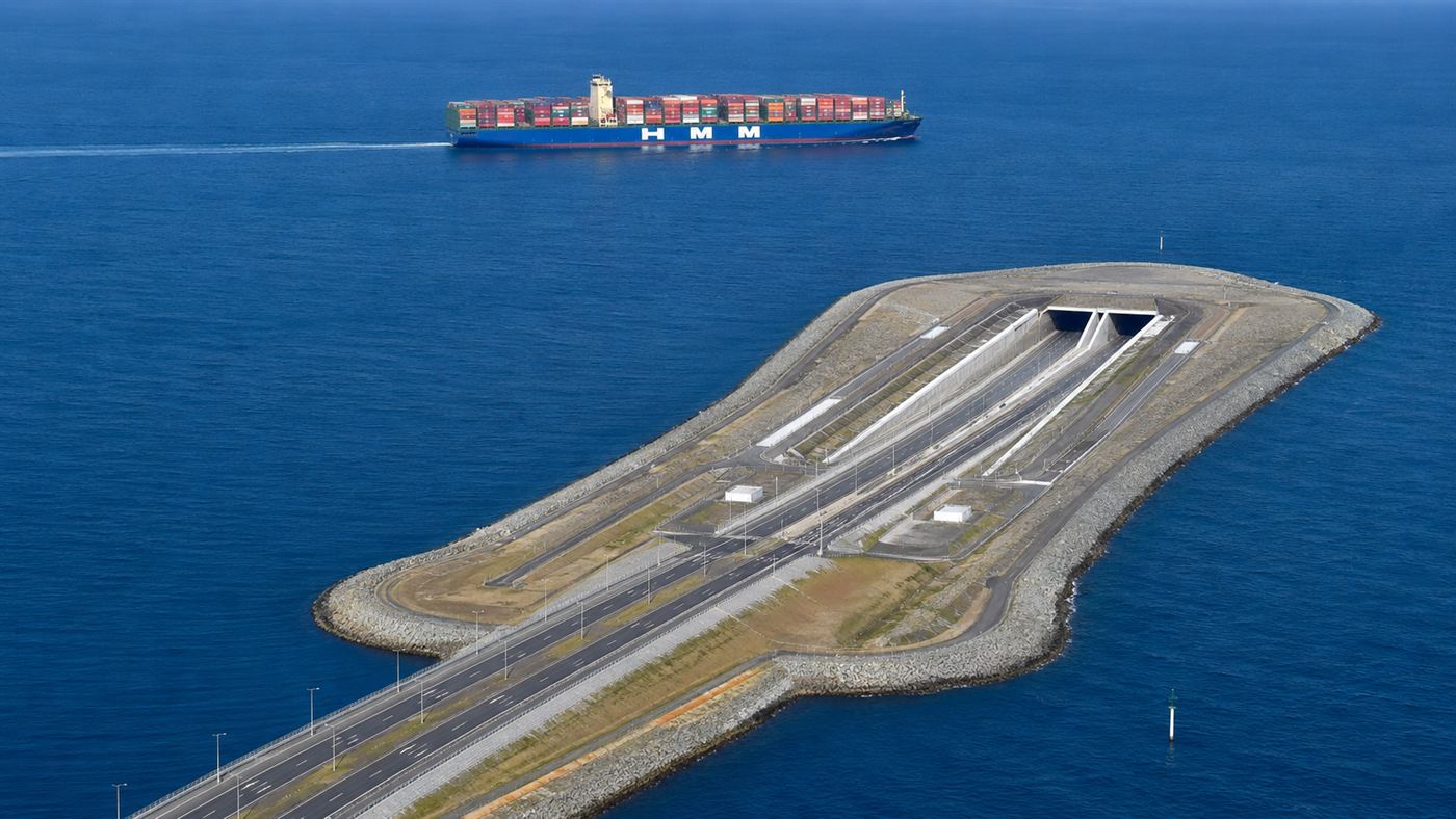 The Hong Kong-Zhuhai-Macau Bridge descending into an undersea tunnel portal on an artificial island as a ship passes