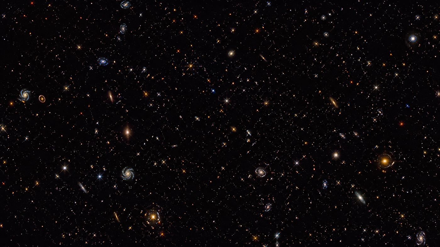 A deep field image from a space telescope showing thousands of distant galaxies scattered across black space
