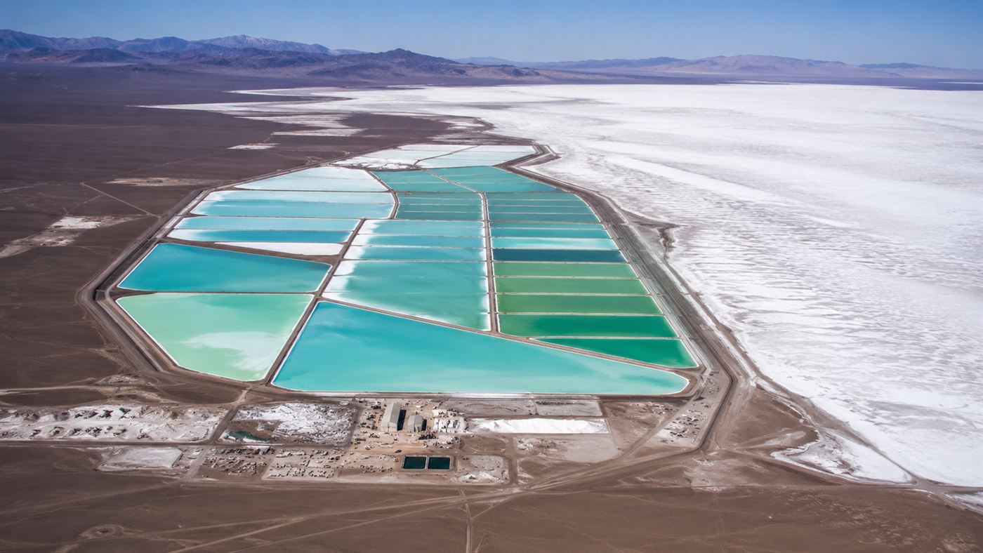Large turquoise lithium brine evaporation ponds beside a salt flat in a high desert