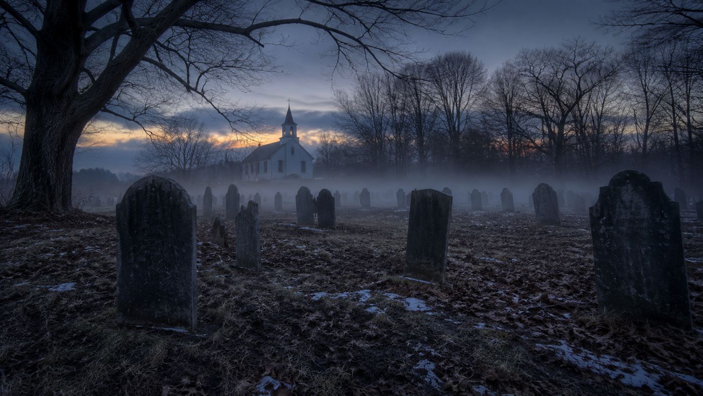 A misty New England country graveyard at dusk with old slate headstones under bare trees, evoking the Mercy Brown vampire case
