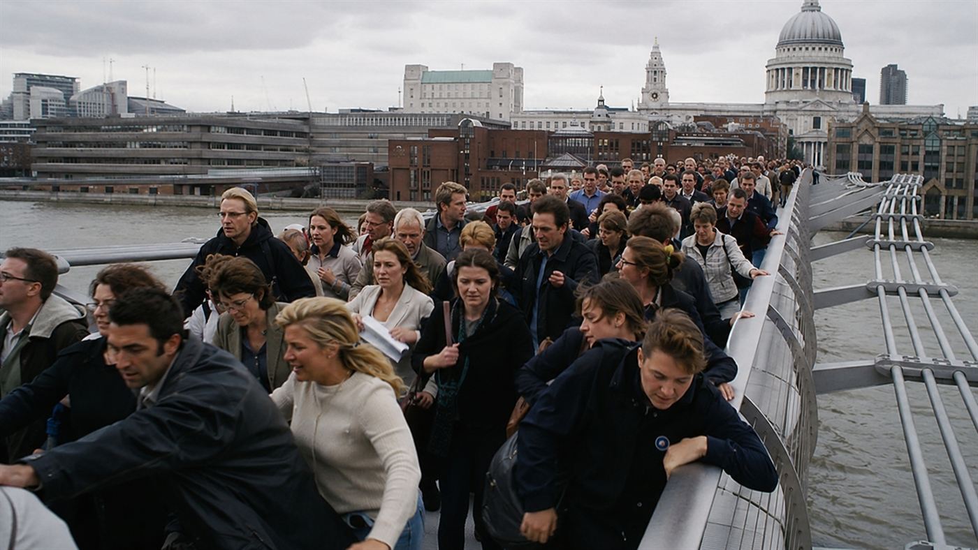 A dense crowd of pedestrians on the swaying London Millennium Bridge gripping the handrails in 2000