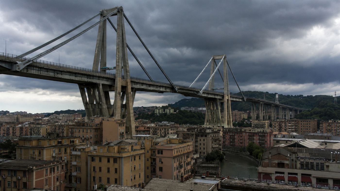 The Morandi Bridge in Genoa, its concrete A-shaped towers carrying the motorway over the city under a dark storm sky