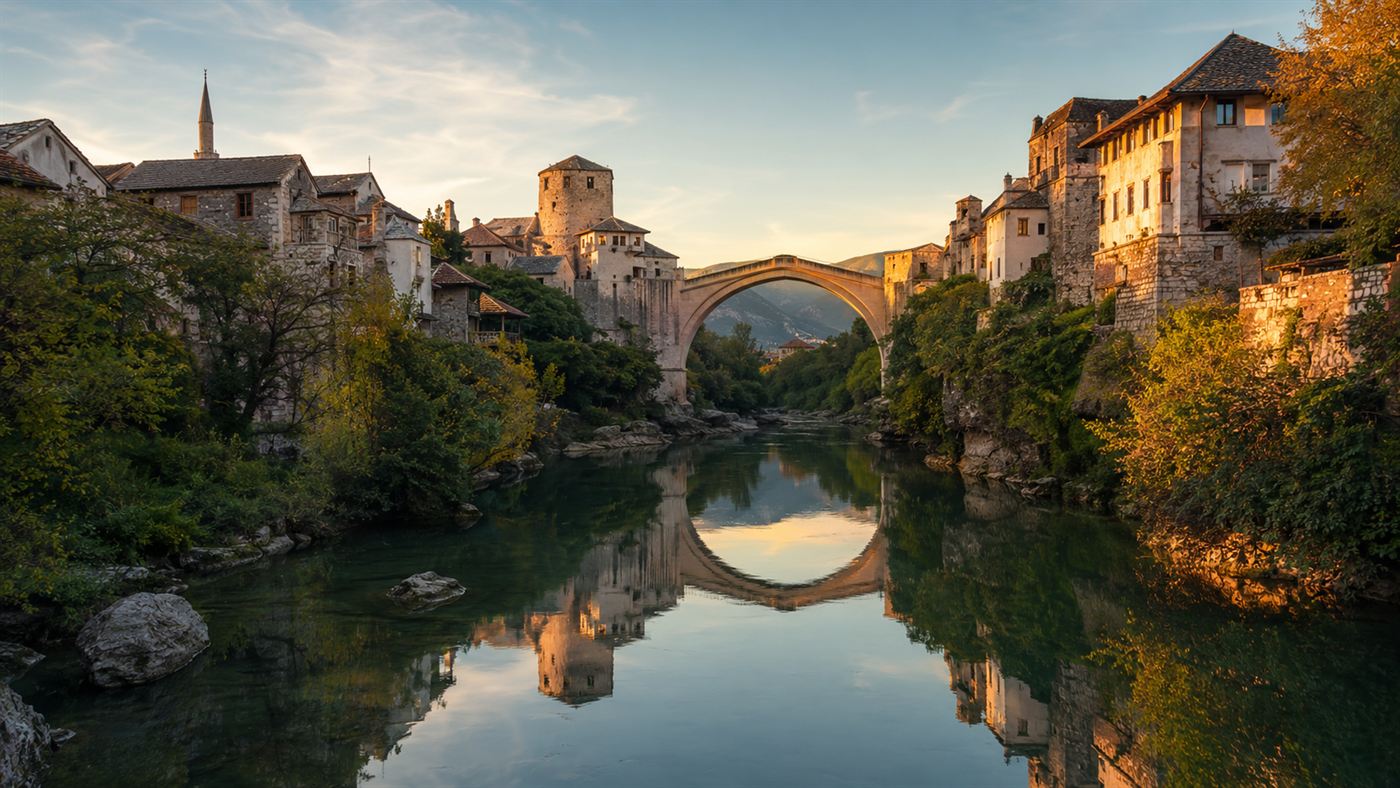 The rebuilt bridge and old town of Mostar reflected in the Neretva river at golden hour