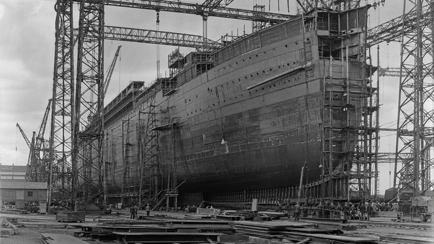 A huge Olympic-class ocean liner under construction in the towering gantries of the Harland and Wolff shipyard in Belfast
