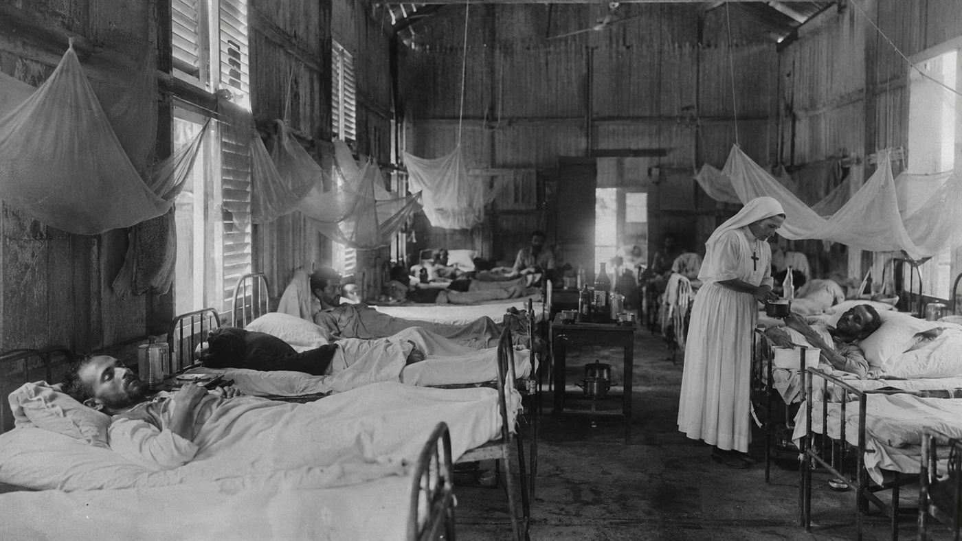 A makeshift 1880s hospital ward in the Panama jungle with sick canal workers under mosquito netting