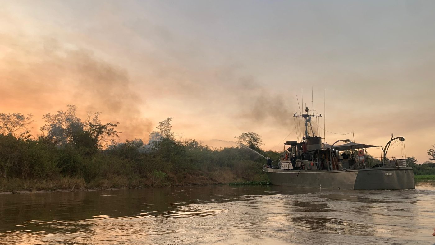 Embarcação do Corpo de Bombeiros joga água durante o combate a incêndio na área queimada do Pantanal, em Mato Grosso do Sul