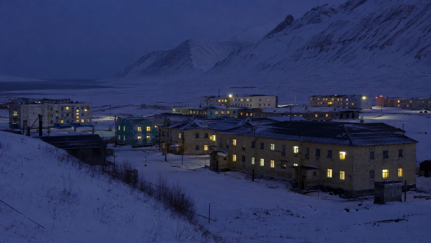 The remote Russian Arctic town of Pevek under deep snow with warm lights glowing, powered by the floating nuclear plant