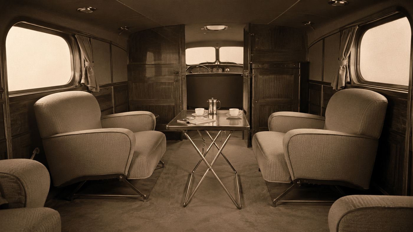 The spacious flat-floored interior of the 1936 Stout Scarab with movable armchair-style seats and a small table, like a small lounge