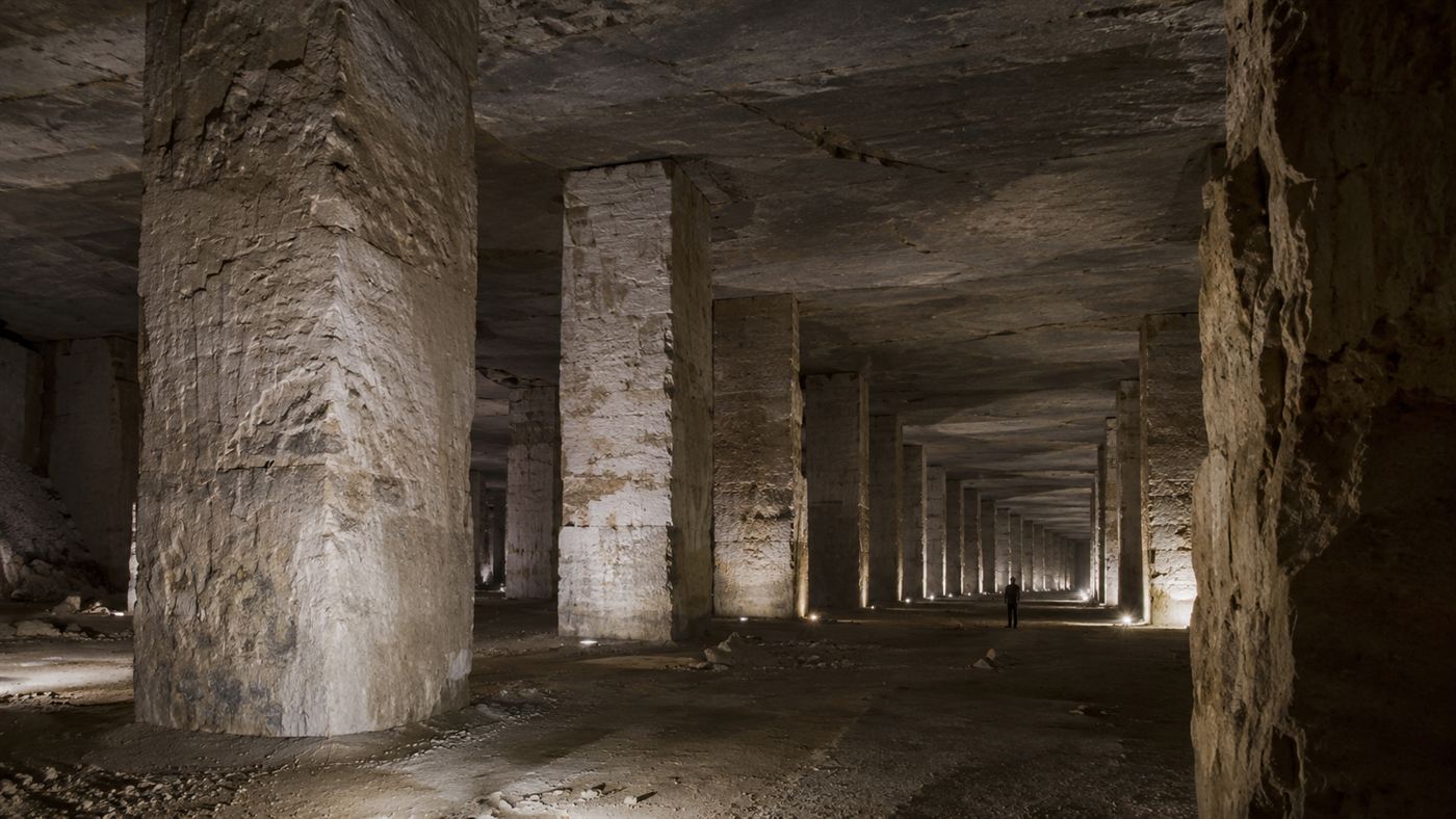 Rows of massive square limestone pillars supporting the roof of a vast underground space