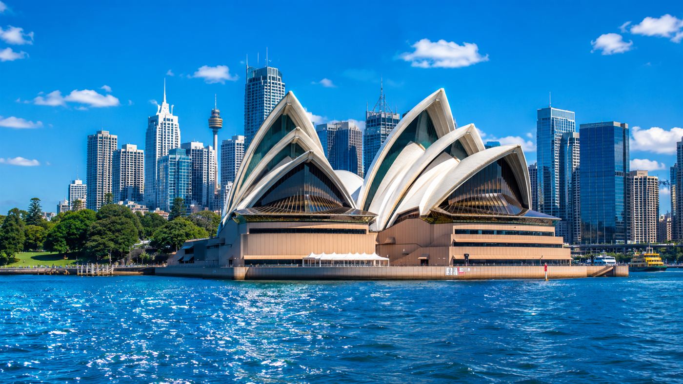 The white sail-like shells of the Sydney Opera House gleaming on the harbour against a bright blue sky