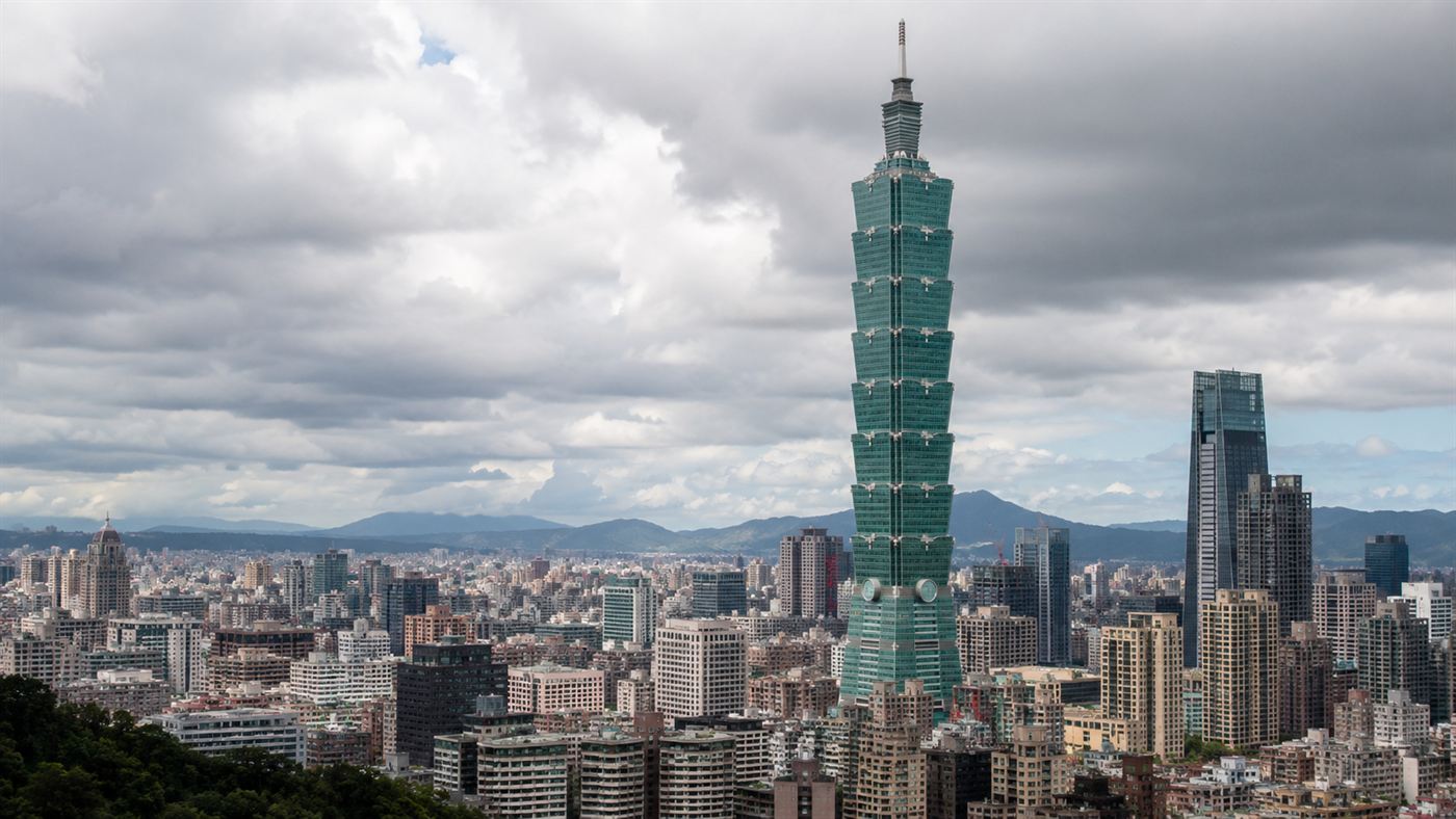 The Taipei 101 skyscraper rising above the Taipei skyline against a cloudy sky