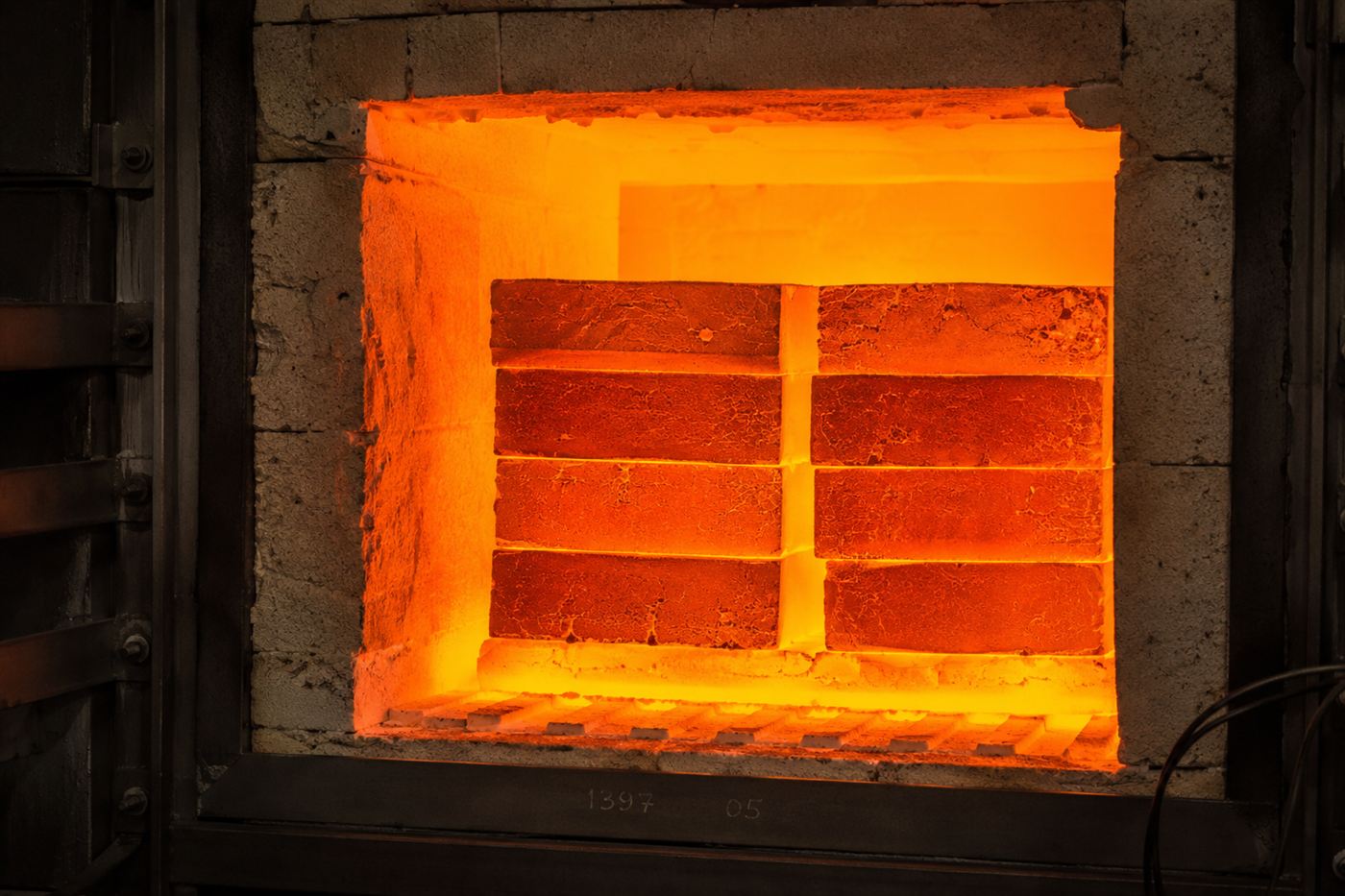 Stacked carbon blocks inside an insulated chamber glowing brilliant white and orange hot, a thermal battery storing energy as heat