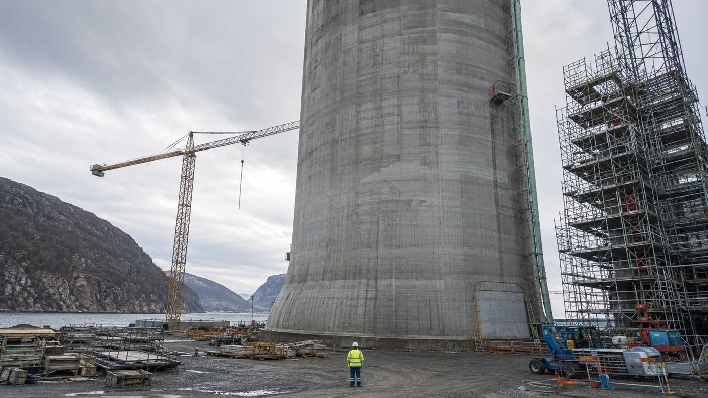 A tiny engineer dwarfed at the base of one of the Troll A platform's giant concrete legs during construction