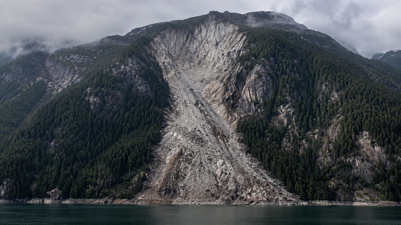 A huge raw landslide scar gouged down the steep forested slope of Monte Toc above the Vajont reservoir