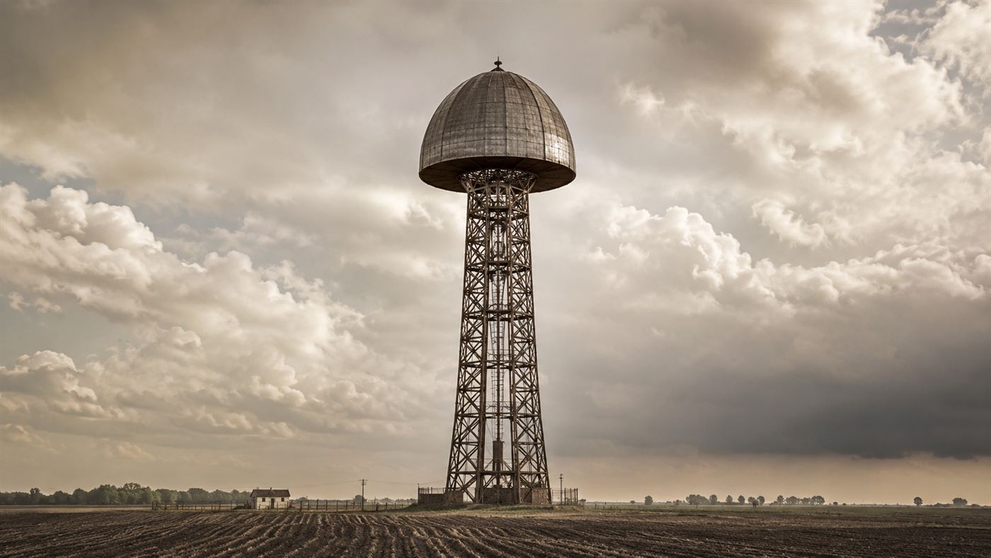 The Wardenclyffe Tower, a tall lattice tower with a mushroom-shaped dome, rising over Long Island farmland around 1903