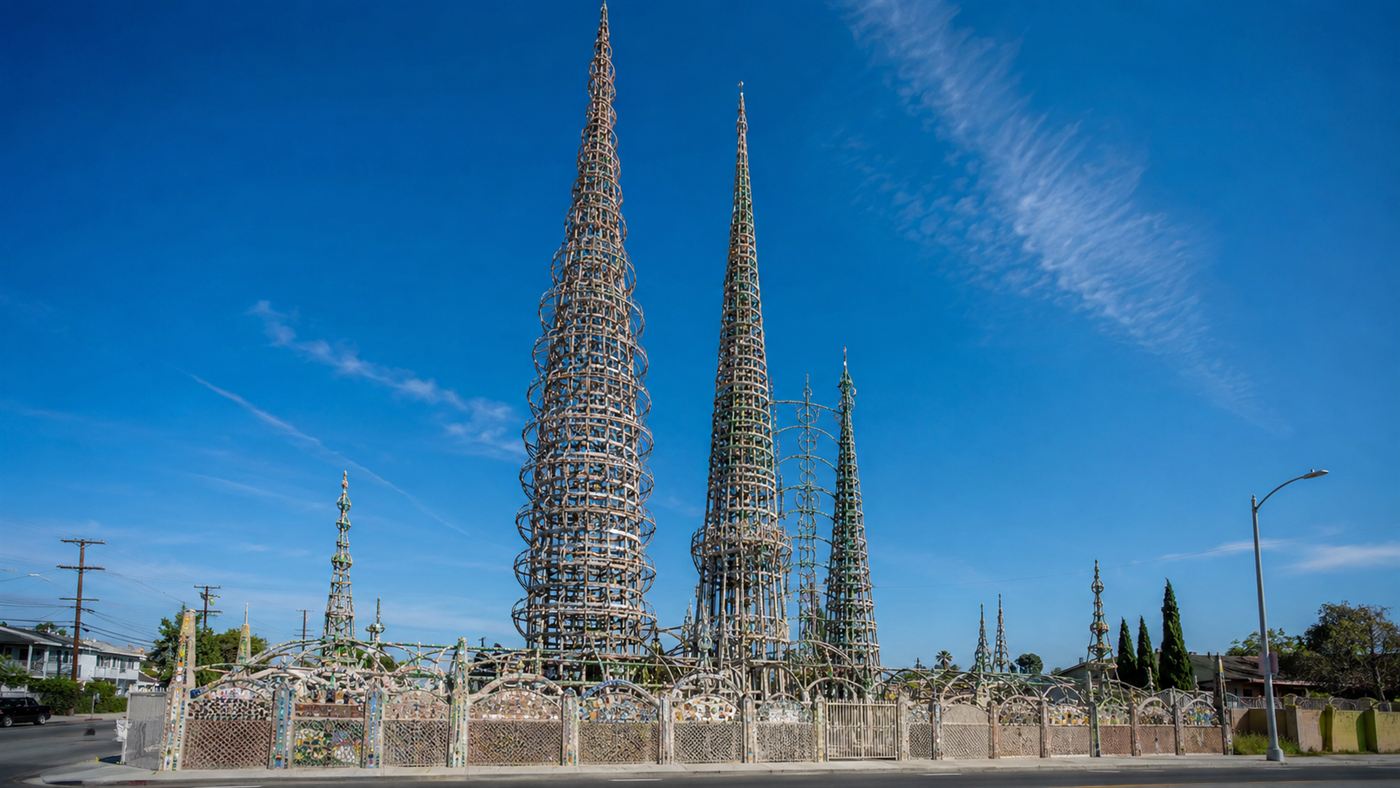 The soaring lace-like steel spires of the Watts Towers covered in colorful mosaic against a blue Los Angeles sky
