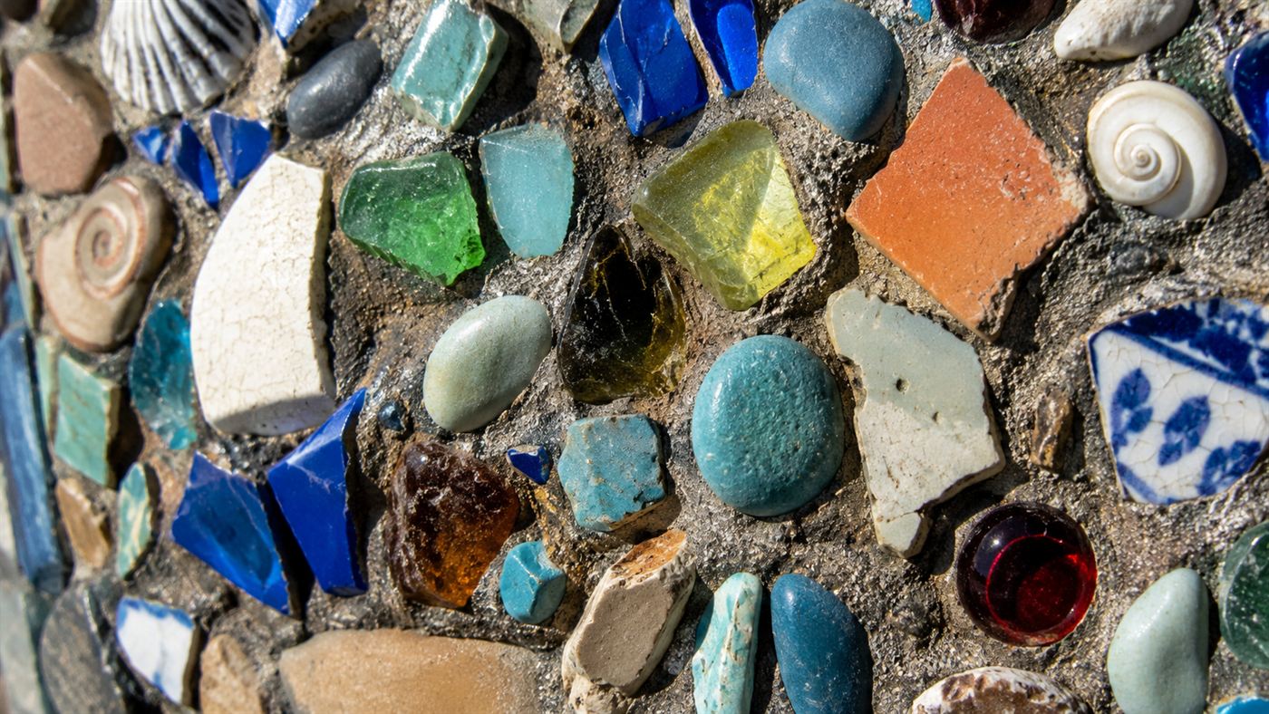 A close-up of the Watts Towers surface showing embedded broken tiles, colored glass, shells and pottery