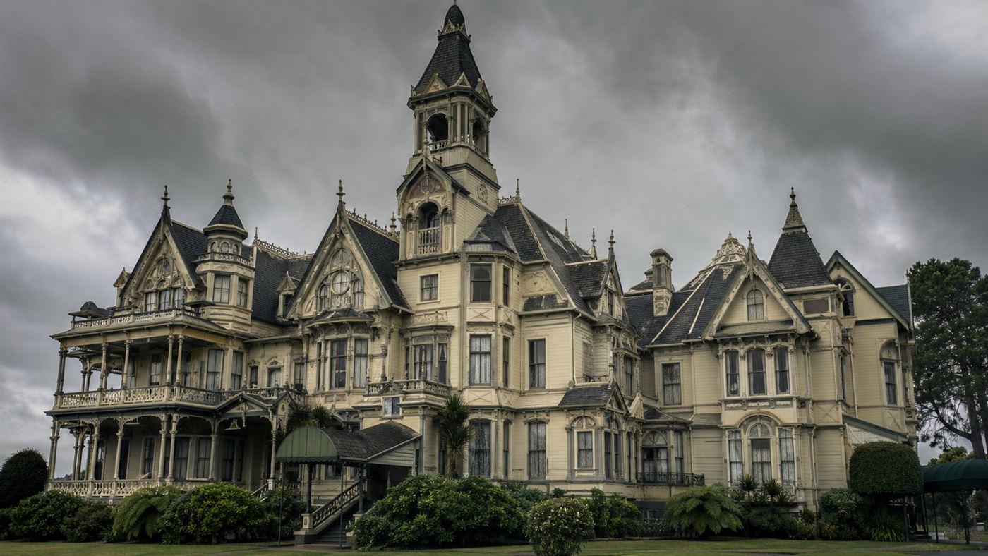 The sprawling Victorian facade of the Winchester Mystery House under a moody sky