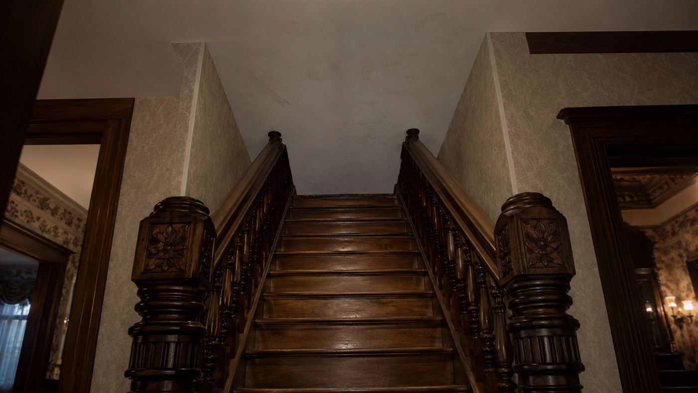 A wooden staircase inside the Winchester Mystery House that climbs straight into a blank ceiling