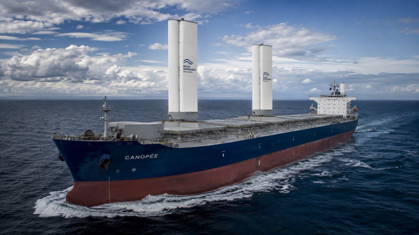 A wind-powered cargo ship at sea with two tall rigid wing sails on its deck