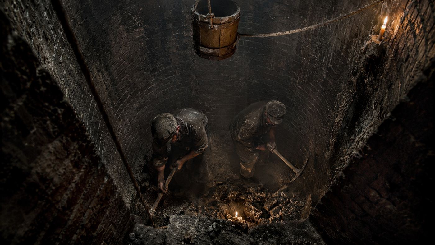 Victorian labourers digging at the bottom of the Woodingdean Well shaft by candlelight