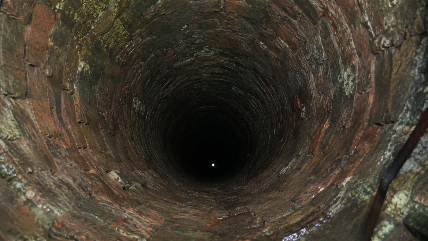 Looking down the deep brick-lined shaft of the Woodingdean Well into darkness